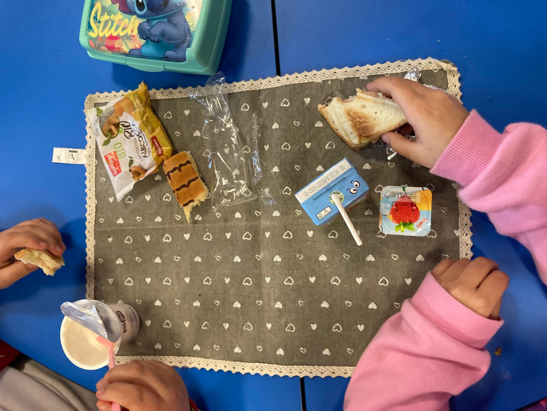 Copertina del laboratorio "Contrasto alla discriminazione economica" condotto da Labins, raffigurante un banco di scuola visto dall'alto su cui due bambine/i fanno merenda