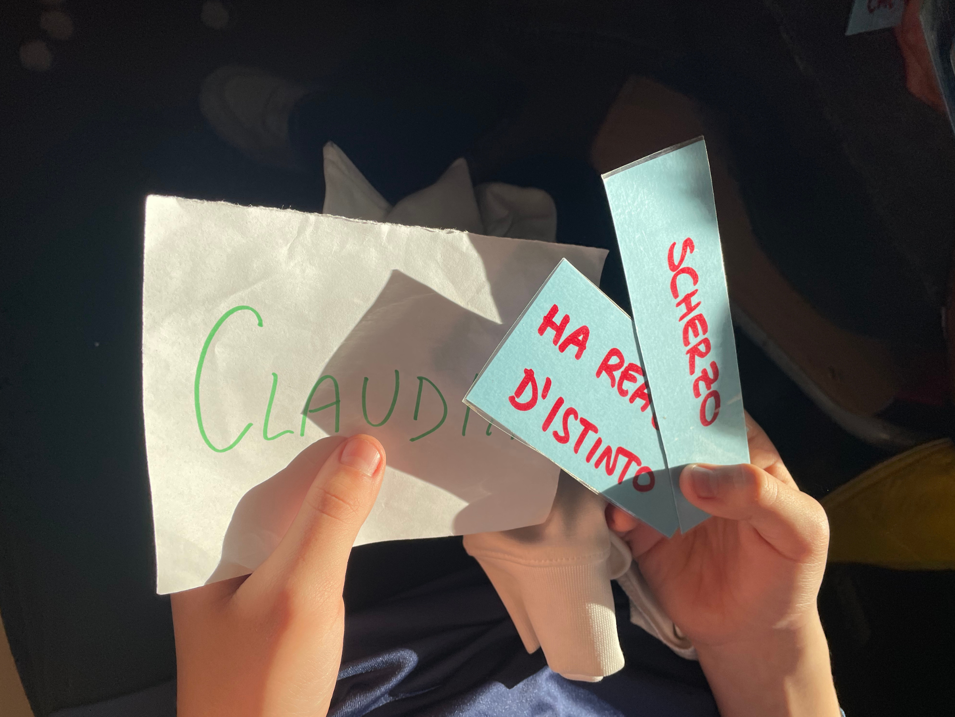 Copertina del laboratorio Bullismo e Cyberbullismo rappresentativa di delle mani di uno studente che tiene in mano tre biglietti: uno più grande con su scritto Claudio e altri due bigliettini più piccoli con su scritto "ha reagito d'istinto" e "scherzo"
