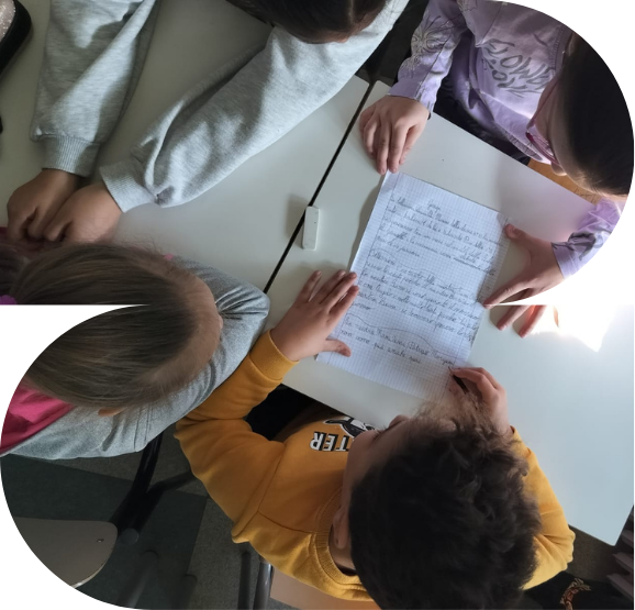 Immagine del laboratorio Pensiero computazionale e cittadinanza digitale condotto da Un sogno per tutti scs raffigurante un gruppo di bambine e bambini attorno ad un tavolo in classe visti dall'alto che guardano tutte insieme un foglio scritto da loro
