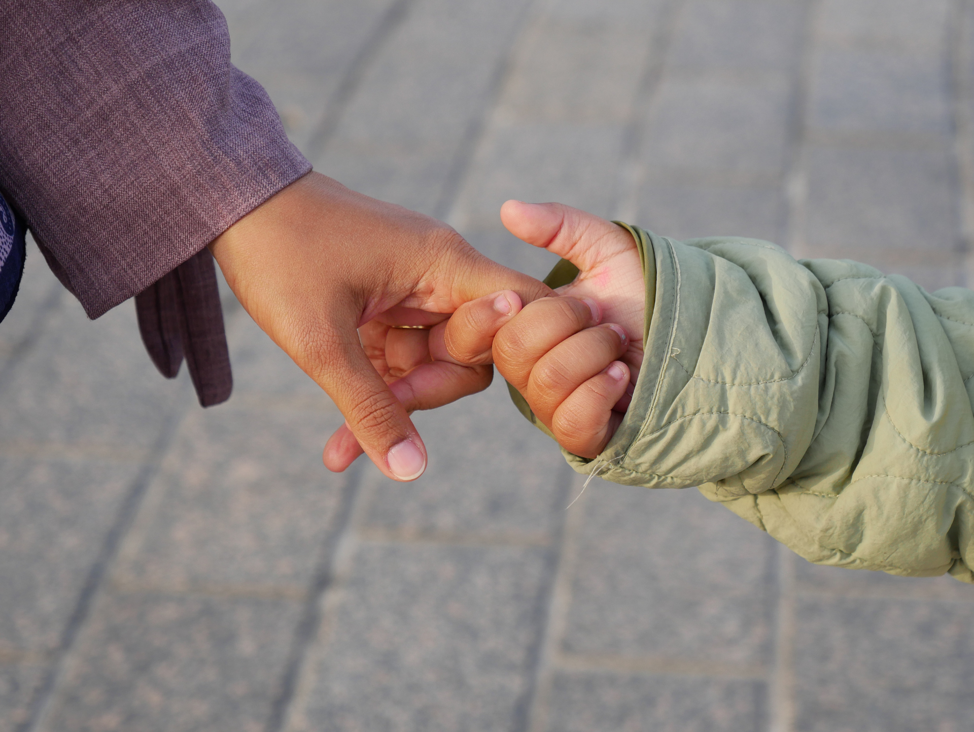 Foto di una persona adulta che tiene per mano una bambina o bambino a passeggio